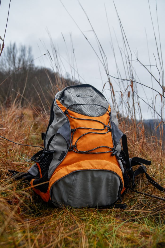 Captivating orange hiking backpack in a tall grassy field, perfect for adventure and travel stock imagery.