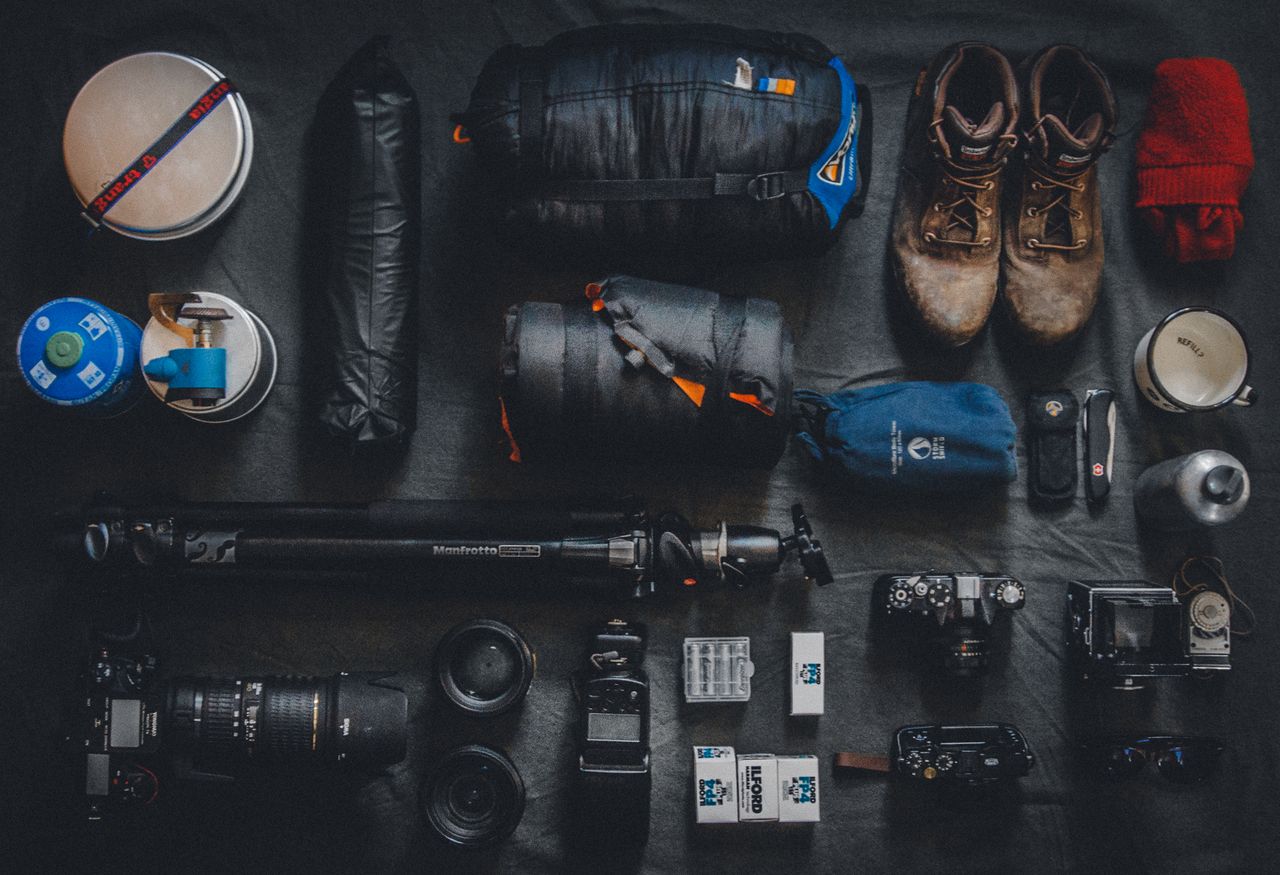 Flat lay of outdoor camping and photography equipment neatly organized.